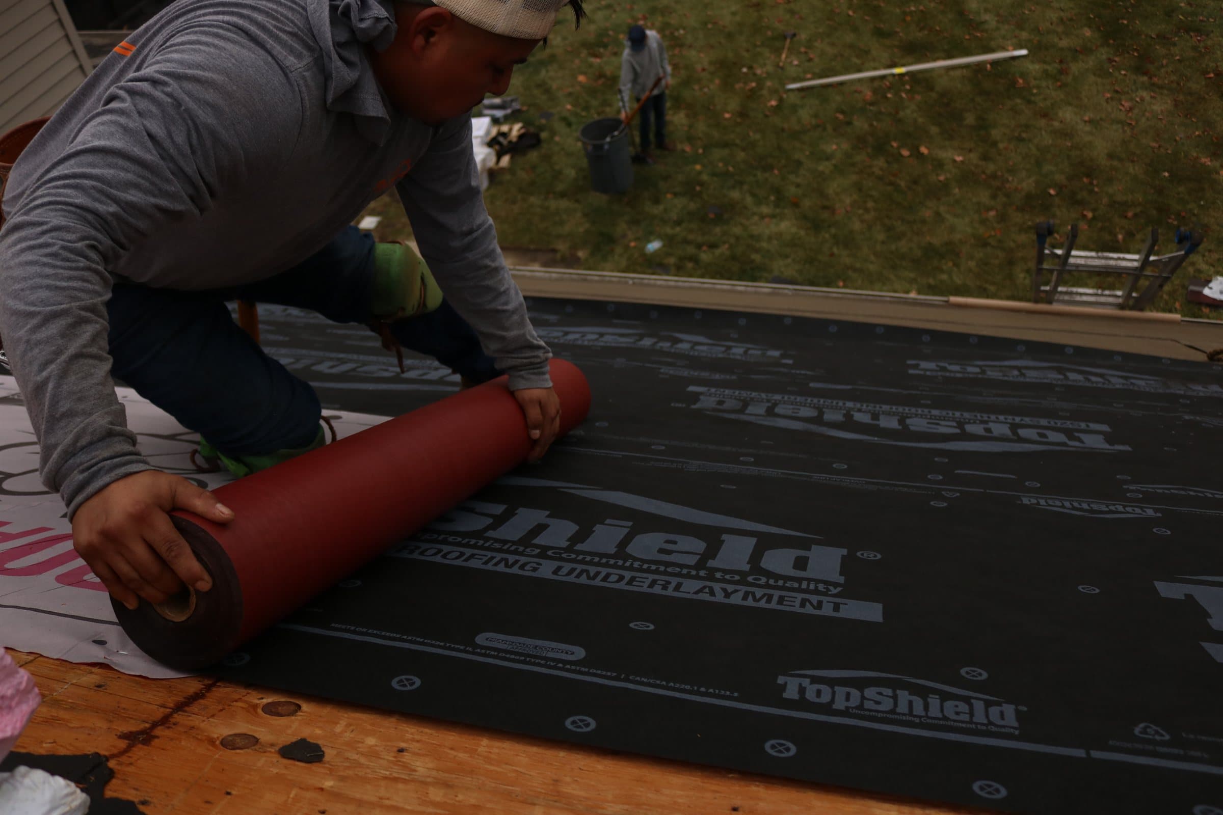 Synthetic underlayment rolled and fastened across the roof field before shingles go down